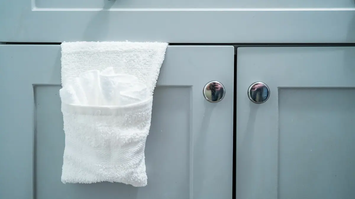 Small rental bathroom organized with removable bins, hooks, towels, and compact shelves